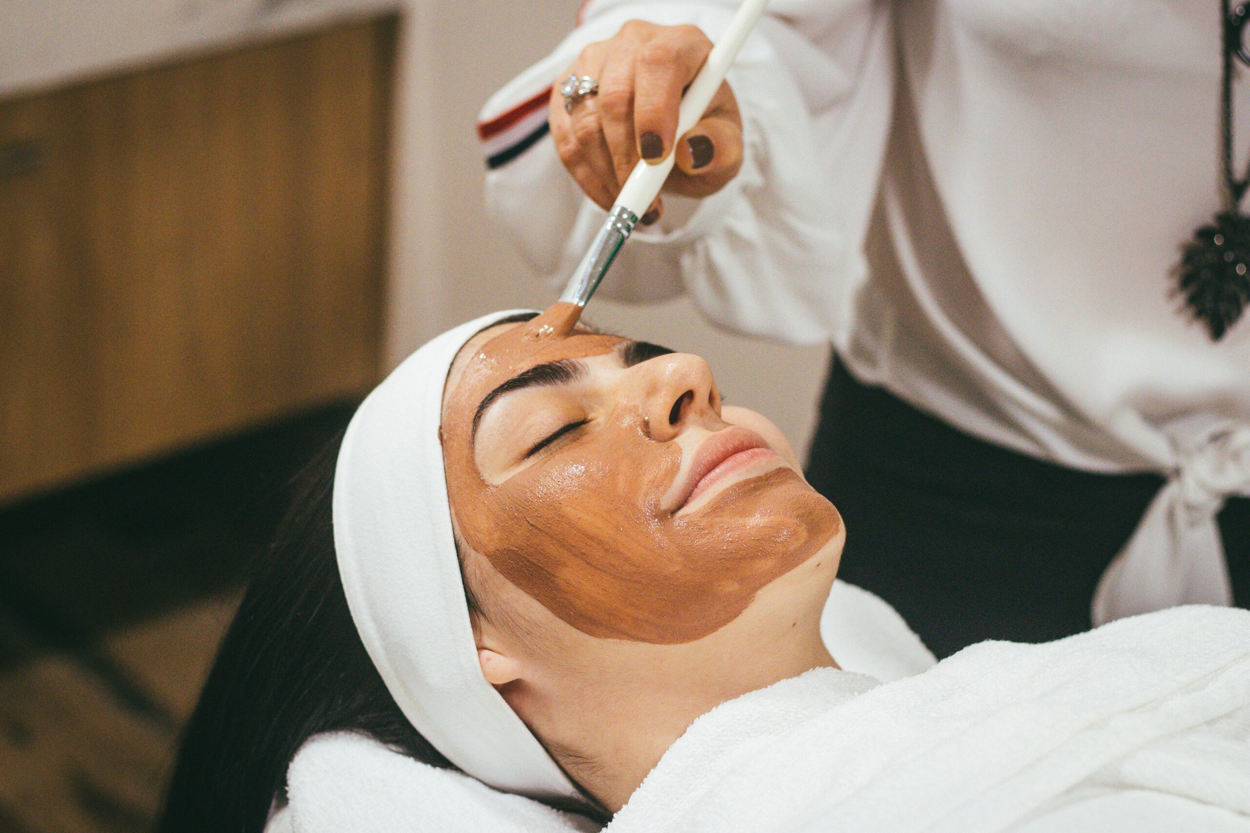 woman at spa getting face mask applied with brush