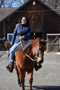 Riding a horse outside a barn.