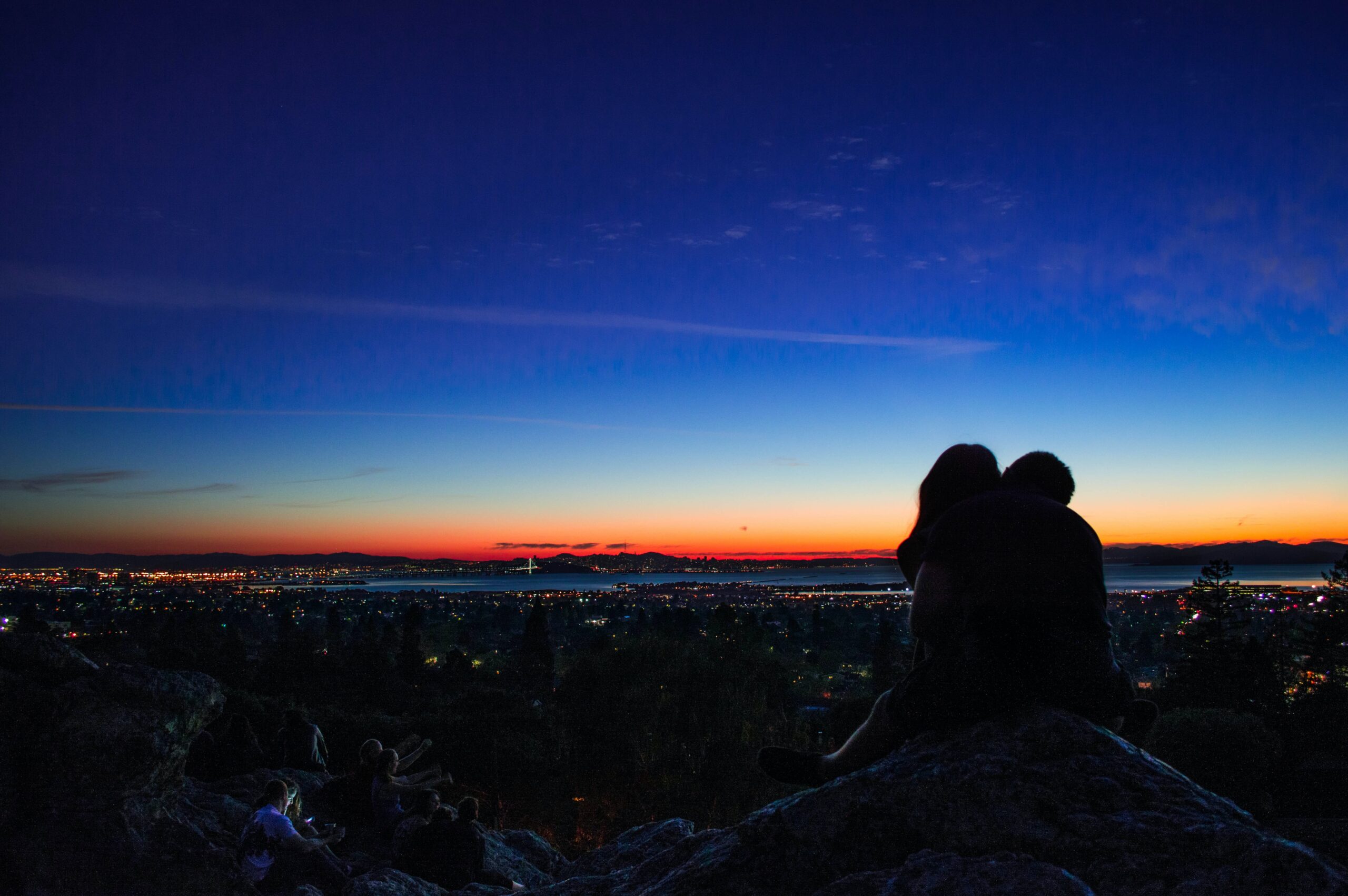 Silhouette of Couple on Mountain Above Town at Sunset