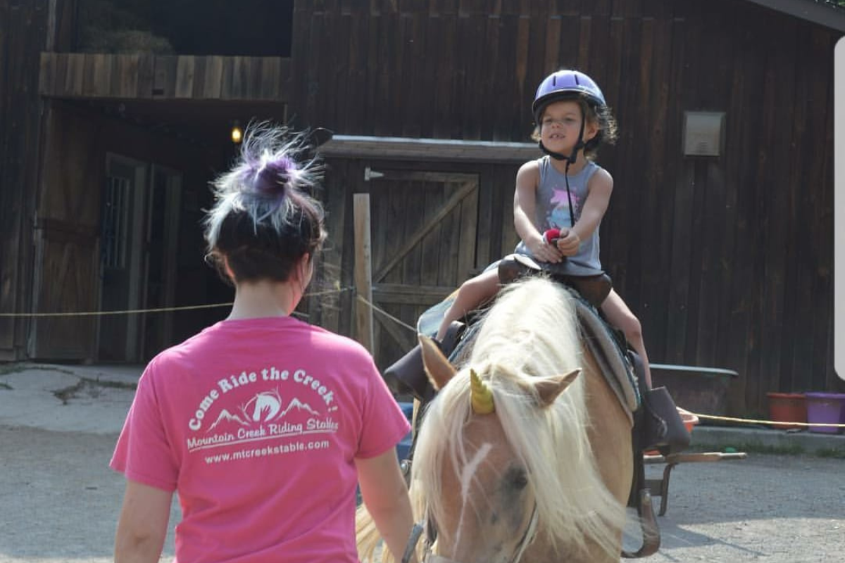 younger rider on horseback during a pony ride led by a trail guide