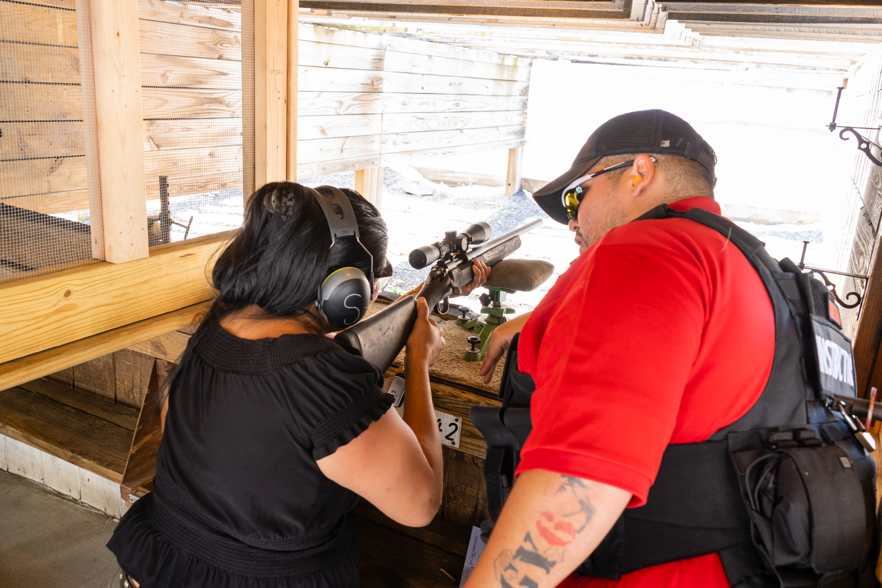 Woman practicing shooting firearms at a shooting range with a supervisor next to her observing