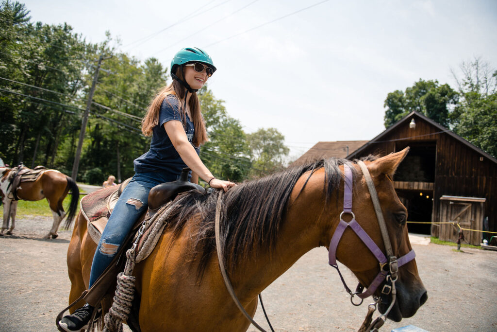 woman in jeans and blue tshirt on horse