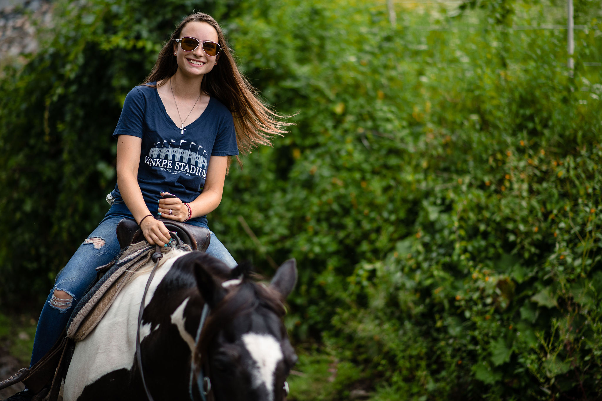 Woman in Navy Blue Tshirt Riding Black and White Horse in the Woods